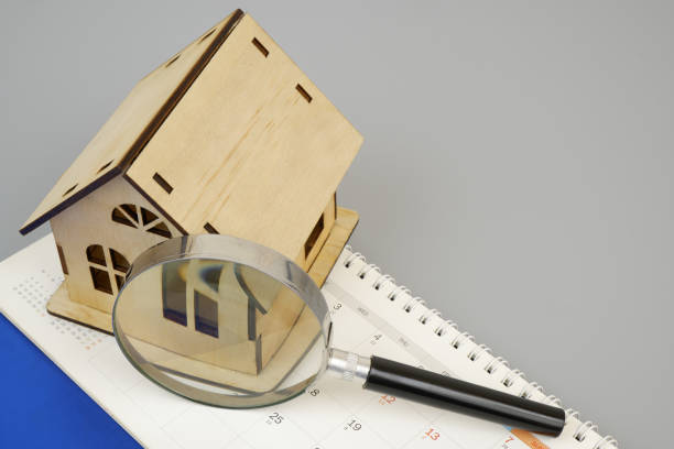 istock Wooden house model under magnifying glass on calendar with copy space for text. 2189583624