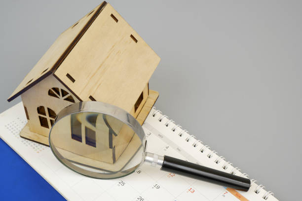 istock Wooden house model under magnifying glass on calendar with copy space for text. 2189583892