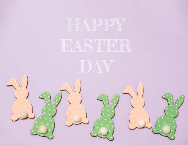 istock Group of Easter bunny figurines are arranged in a row on a purple background 2189584016