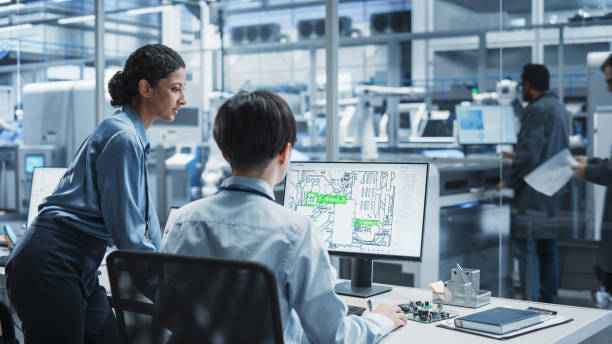 istock Hispanic Female Manager And Asian Male Engineer Using Desktop Computer With Microchip Blueprints at the Factory With Robotic Arms. Colleagues Discussing Production Hardware For Electronics. 2189585822