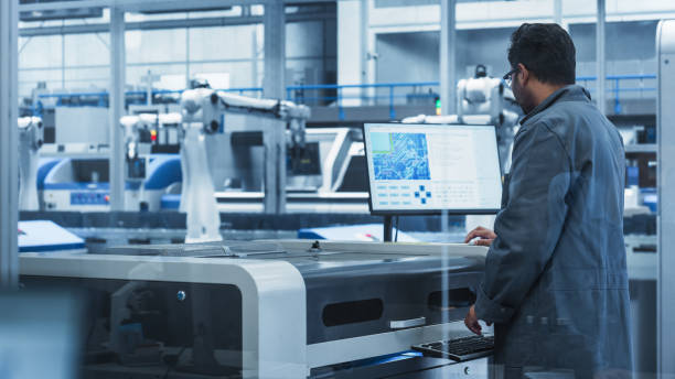 istock Indian Male Assembly Line Worker Using Soldering Jet Printer For Production Of Printed Circuit Boards At Autonomous Factory With Robotic Arms. Man Working On Computer Parts For High-Tech Devices. 2189585999