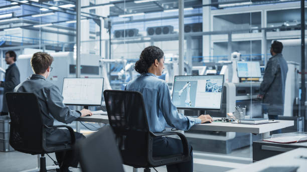 istock Caucasian Male Programmer And Hispanic Female Automation Engineer Using Desktop Computers To Control Assembly Line With Robotic Arms At Modern Factory. Colleagues Working On Production Of Electronics. 2189586391