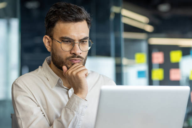 istock Focused man in office environment, wearing glasses and working on laptop, demonstrating concentration and thoughtful analysis for professional decision-making or strategic planning at work. 2189589010