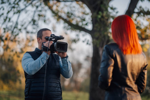 istock Videographer recording a female journalist doing a piece to camera in a park 2189590454