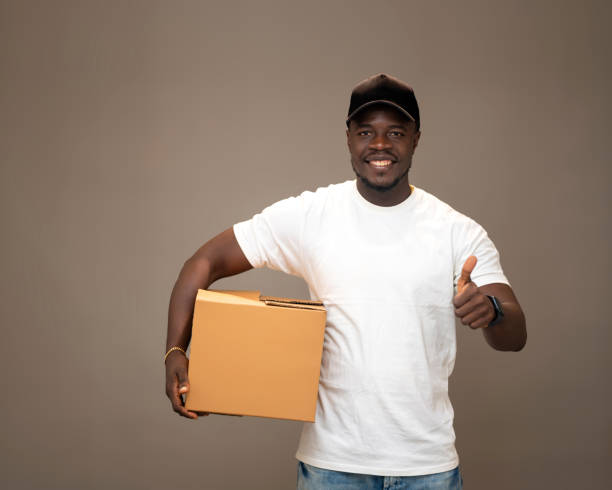 istock Neatly Dressed Black American Delivery Man Smiling with a Cardboard Box 2189593931