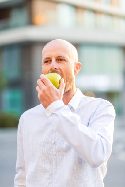istock Businessman eating green apple outside office building 2189594205