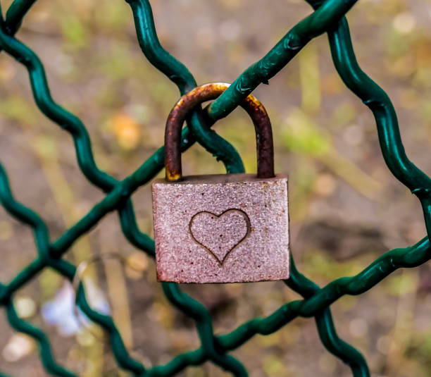 istock A rusty lock with a heart engraved on it is hanging from a chain link fence 2189594588