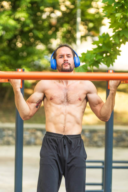 istock Young man wearing headphones doing pull ups in a park 2189594943