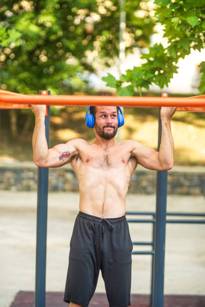 istock Young man listening music doing pull ups workout exercise outdoor gym 2189594947