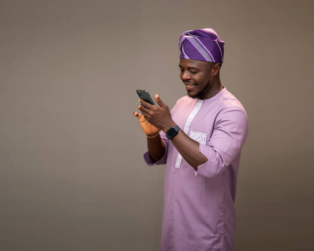 istock Nigerian Man in Native Attire Browsing His Phone with a Happy Expression 2189595329
