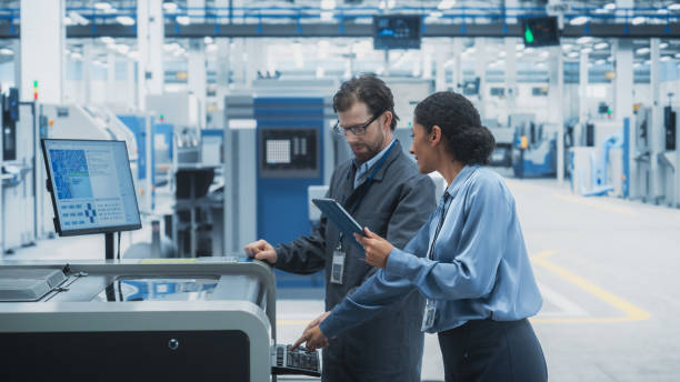 istock Caucasian Male Chief Engineer And Hispanic Female Supervisor Using Tablet And Talking At Electronics Factory. Man Using Soldering Jet Printer, Explaining Process Behind Production Of New Microchip. 2189597747