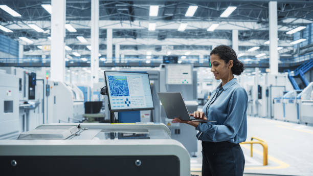 istock Hispanic Female Engineer Using Laptop To Control Soldering Jet Printer On Electronics Factory. Woman Working On Production Of Innovative Circuit Boards For Complex Artificial Intelligence Systems. 2189598362
