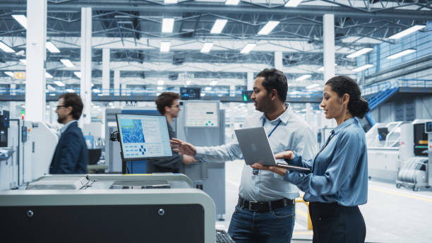 istock Indian Male Chief Engineer And Hispanic Female Supervisor Using Laptop And Talking At Electronics Factory. Man Using Soldering Jet Printer, Explaining Process Behind Production Of Circuit Boards. 2189598416