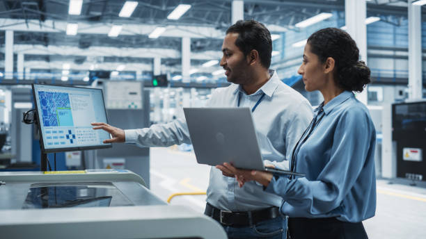 istock Indian Male Industrial Engineer And Hispanic Female Supervisor Using Laptop And Talking At Electronics Factory. Man Using Soldering Jet Printer, Explaining Process Behind Production Of Circuit Boards. 2189598466