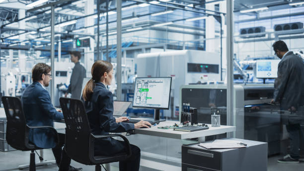 istock Automated Electronics Factory With Robotic Arms: Diverse Specialists Working On Production Line Of Circuit Boards For Modern High Tech Devices. Engineers, Assembly Line Workers, Managers Working. 2189598571
