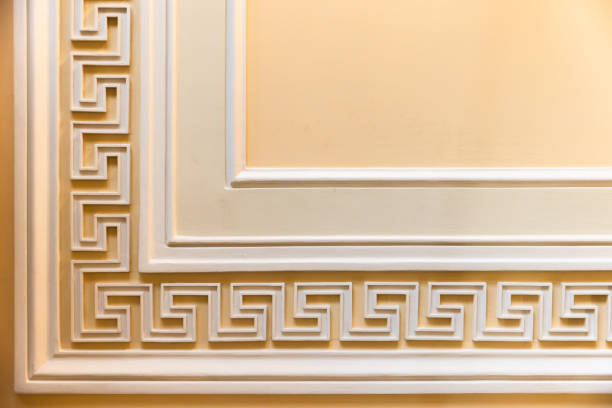 istock Meander motif over yellow backdrop. Classic wall moulding 2189600997