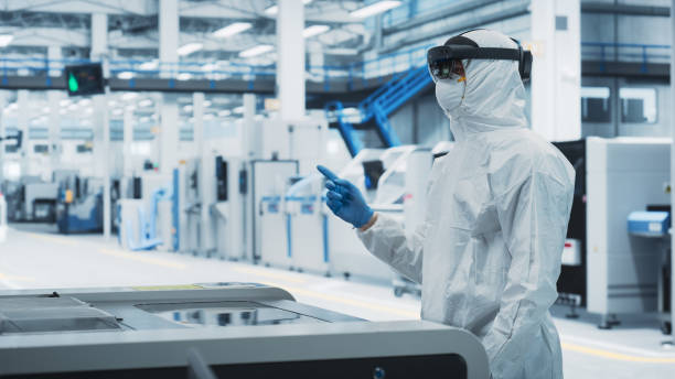 istock Sterile Coverall Wearing Engineer Uses Augmented Reality Headset to Interact With Models of Silicon Microchip in Manufacturing Facility, Precision Engineering of Advanced Computer Hardware 2189603406