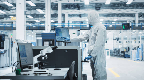 istock Printed Circuit Board Production At an Electronics Factory: Scientist In Sterile Suit Using Soldering Jet Printer To Make Motherboards For Powerful Processors. Computer Hardware Manufacturing Facility 2189603490