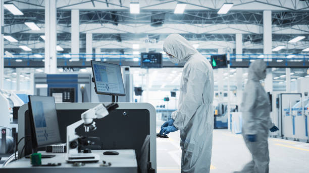 istock Printed Circuit Board Production At Electronics Factory: Scientist In Sterile Suit Using Soldering Jet Printer To Make Motherboards For Powerful Processors. Computer Hardware Manufacturing Facility. 2189603505