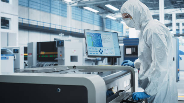 istock Printed Circuit Board Production At Electronics Factory: Scientist In Sterile Suit Using Soldering Jet Printer To Make Motherboards For Powerful CPU. Powerful Computer Hardware Manufacturing Facility. 2189603750