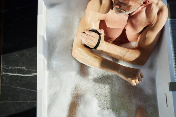 istock Mature Man Rubbing Skin with Sponge Taking Bath during Body Care Routine Indoors 2189603859