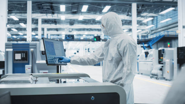 istock Printed Circuit Board Production At Electronics Factory: Scientist In Sterile Suit Using Soldering Jet Printer To Make Motherboards For Powerful CPU. Modern Computer Hardware Manufacturing Facility. 2189603903