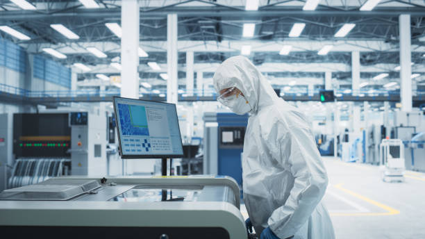 istock Printed Circuit Board Production At Electronics Factory: Technician In Sterile Suit Using Soldering Jet Printer To Make Modern Motherboards For CPUs. Computer Hardware Manufacturing Facility. 2189604231