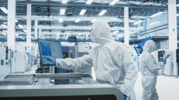 istock Printed Circuit Board Production At Electronics Factory: Technician In Sterile Suit Using Soldering Jet Printer To Make Modern Motherboards For Powerful CPU. Computer Hardware Manufacturing Facility. 2189604244