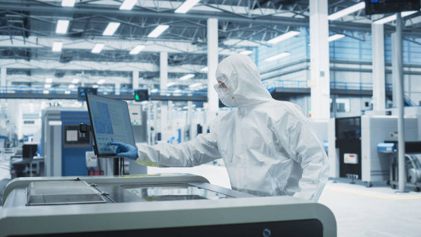 istock Printed Circuit Board Production At Electronics Factory: Technician In Sterile Suit Using Soldering Jet Printer To Make Modern Motherboards For Powerful CPUs. Computer Hardware Manufacturing Facility. 2189604275