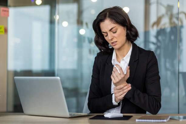 istock Businesswoman experiencing wrist pain while working on laptop in modern office setting 2189605426