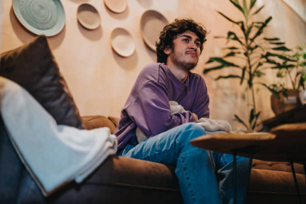 istock Relaxed young man sitting on a modern home couch in casual outfit 2189608634