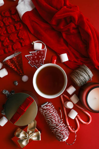 istock Festive Christmas composition with holiday decorations, red cup of tea, candy canes, marshmallows, and gifts on a vibrant red background 2189609680