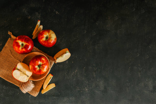 istock Fresh red apples and apple slices arranged on a rustic burlap cloth with a dark textured background, creating a cozy, autumnal food composition 2189610001