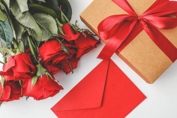 istock A bouquet of red roses, a red envelope, and a gift box adorned with a satin ribbon create a festive and romantic flat lay composition, perfect for Valentine's Day, anniversaries, or special occasions 2189610232