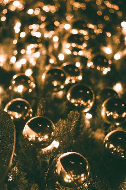 Golden Christmas ornaments on a tree with warm festive lighting and bokeh effects, capturing a cozy holiday ambiance.
