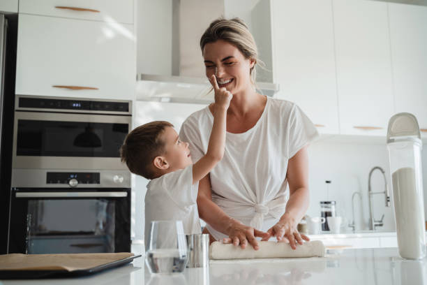 Happy mother and her son baking together in a modern kitchen.