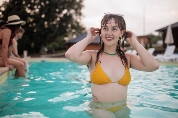 Capture a tourist emerging from a refreshing blue pool, symbolizing summer vacation relaxation. Ideal for projects needing a sense of cool, refreshing holiday visuals.