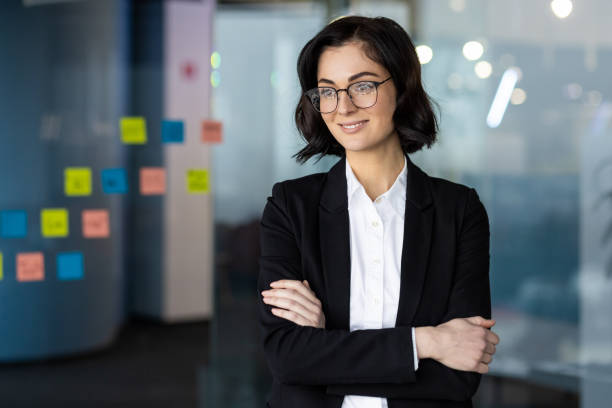 istock Confident young woman in business attire standing in modern office with post-it notes on glass wall 2189614761