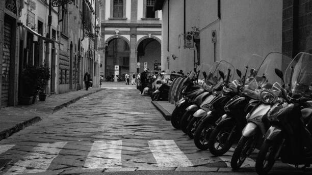 Florence, Italy - October 23, 2023: Rows of scooters line a cobblestone street, symbolizing the vibrance and practicality of life in Florence. The historic backdrop contrasts beautifully with these modern-day vehicles.