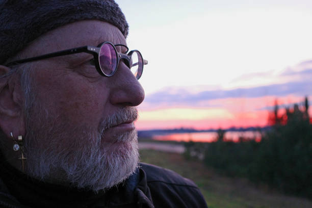 Portrait of an older man looking at beauty of nature. The sun is setting blurred in the background