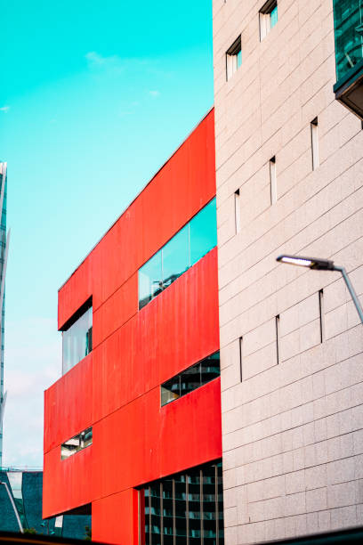 Vivid red and white walls of modern buildings against a clear sky, showcasing an urban architectural design. Represents innovation, urban aesthetics, and contemporary infrastructure.