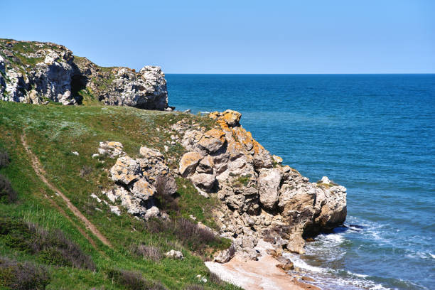 Blue sea, beach with sand rocks and coast with green grass