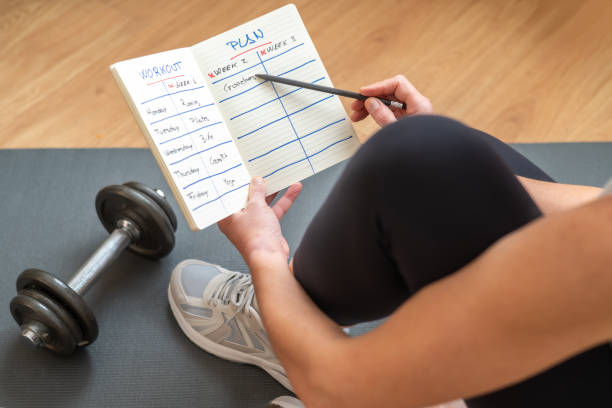 istock Active Female Athlete Preparing Workout Routine On Notepad While Sitting On Yoga Mat With Dumbbells, Promoting A Healthy And Active Lifestyle, Focused On Fitness Goals, Morning Exercise Motivation 2189631895