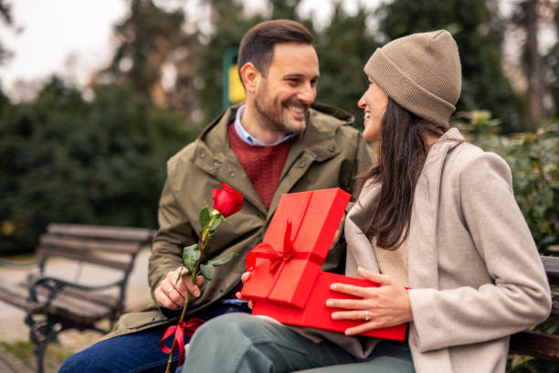 istock Caring Caucasian Man Surprises Girlfriend with Gift in Park 2189634704