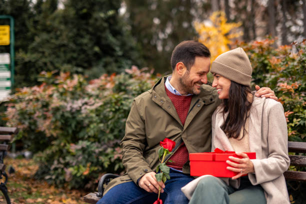 istock Caring Caucasian Man Surprises Girlfriend with Gift in Park 2189634736