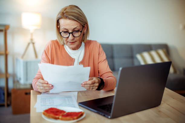 istock Mature woman using laptop while having breakfast at home 2189640192
