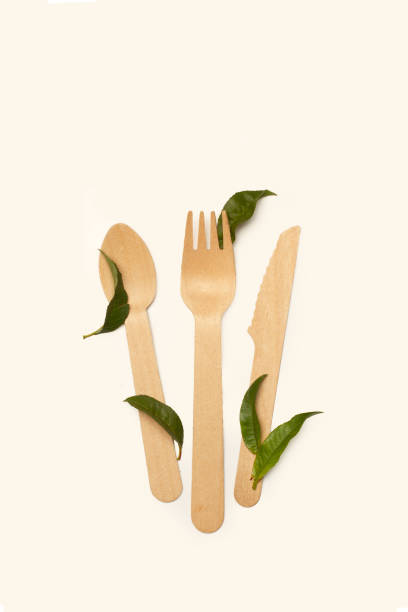 istock Wooden fork, knife, spoon and green leaves on a white background with copy space 2189640981
