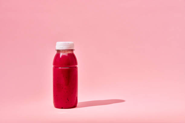 Red Smoothie in Recycled PET Plastic Bottle and Fresh Berries in Plastic Packaging on Pink Background