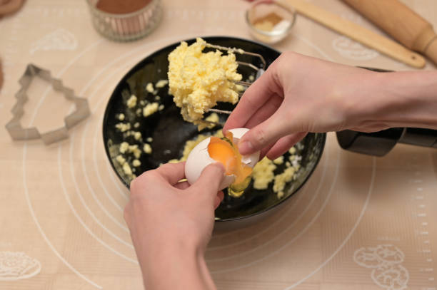 istock Christmas homemade baking, ingredients for baking gingerbread, woman hands breaks an egg in black bowl 2189642077
