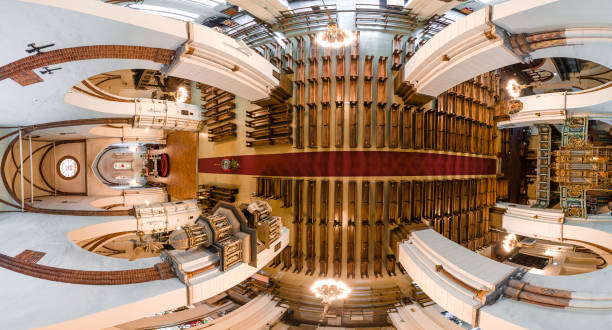 The image captures an aerial view of a cathedral's interior, highlighting symmetrical rows of pews, an ornate altar, intricate ceiling designs, and organ pipes.
